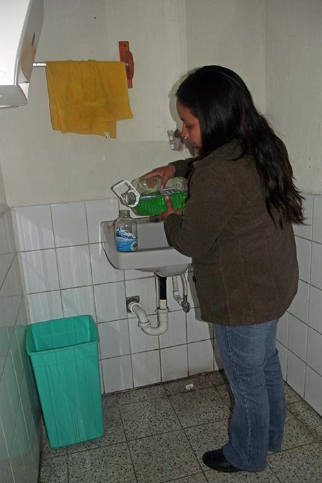 Vanessa llenando los dispensadores plásticos de jabón.
